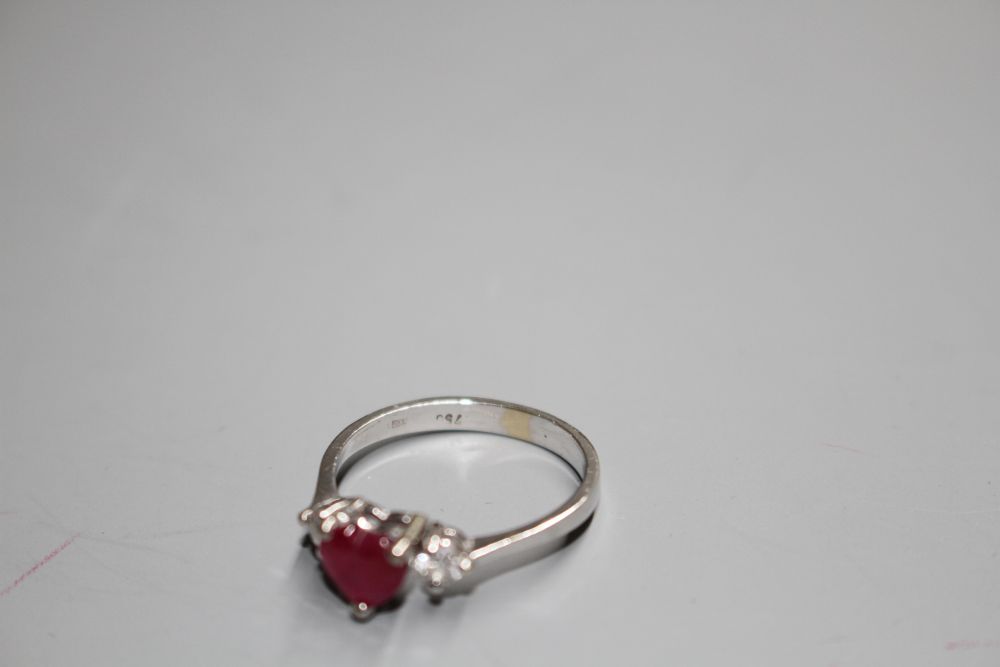 A modern 750 white metal, claw set heart shaped ruby and two round cut diamond set dress ring,